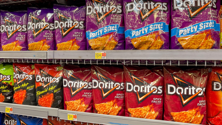 Many bags of Doritos chip varieties on store shelf.