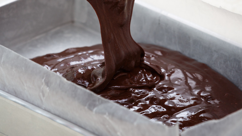 pouring brownie batter in tray