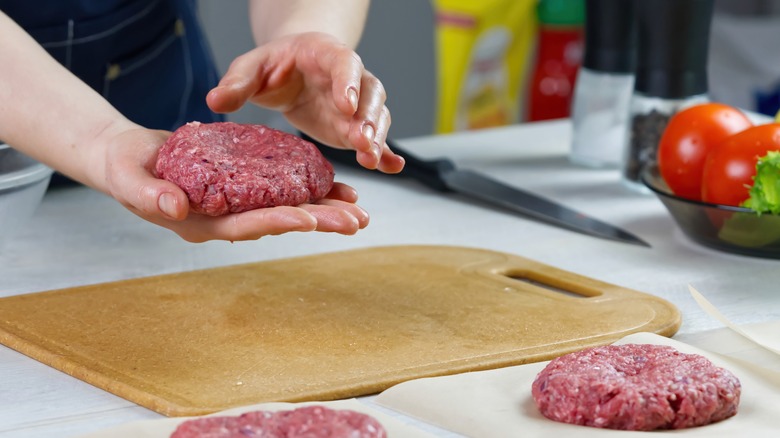 person shaping ground beef into patties