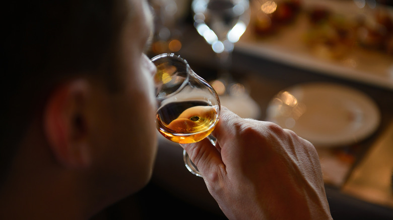 Man smelling the aroma of cognac in drinking glass.