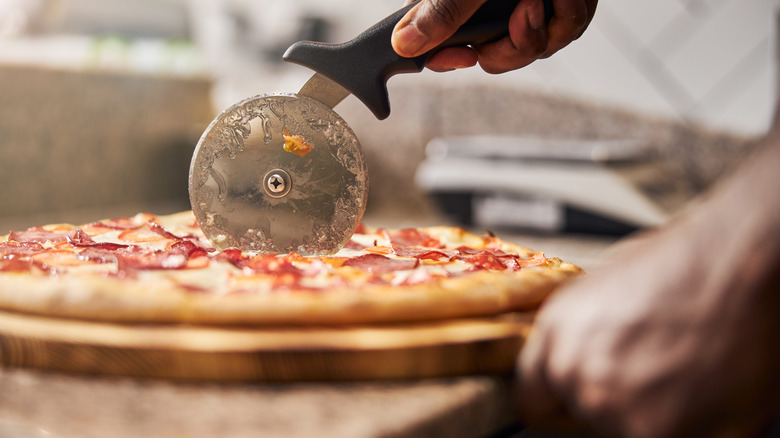 Slicing into a fresh pizza with a cutter