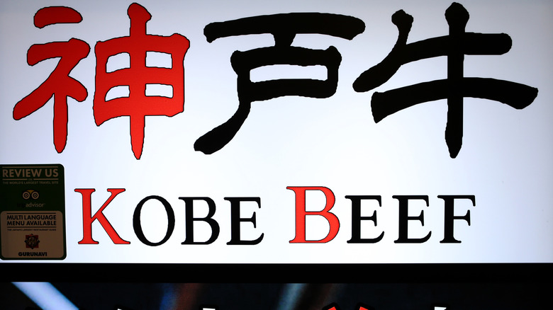 Red, white, and black restaurant sign advertising kobe beef.