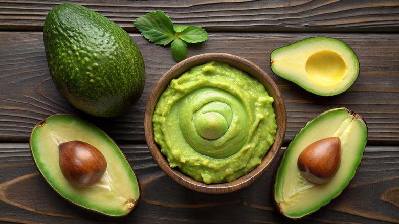 Bowl of guacamole with avocados surrounding it