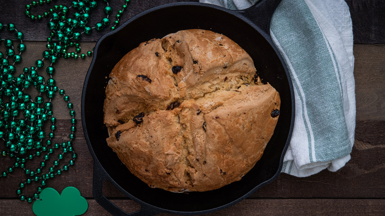 Irish soda bread in a skillet next to a green clover