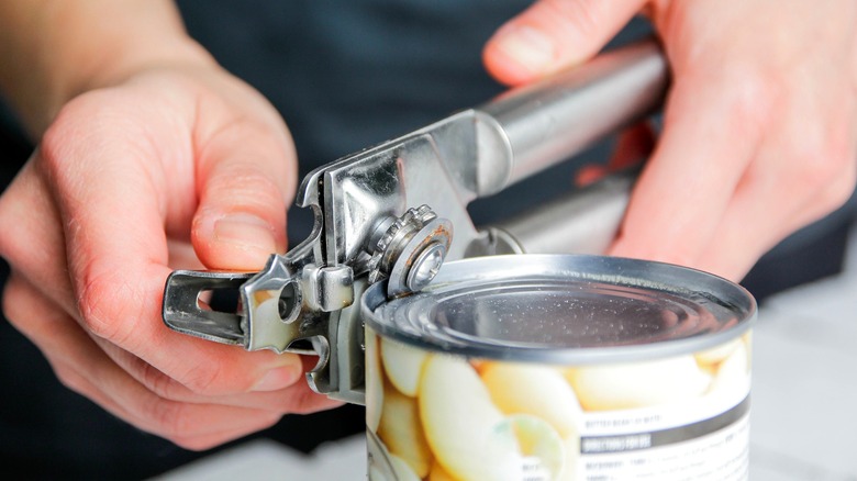 Person opening can of food with can opener