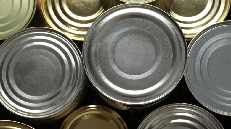 Top view of canned food without labels on dark background