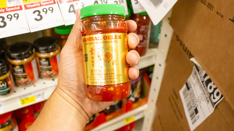 A person holding a jar of Sambal Oelek chili paste