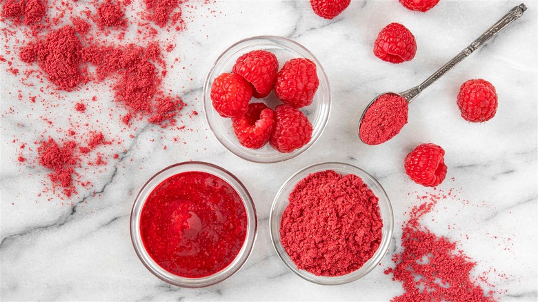 Freeze-dried raspberry powder in spoon with raspberries on side