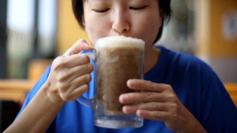 Woman in blue shirt sipping a root beer float.