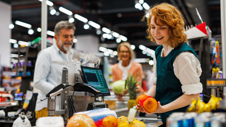 A cashier rings up produce for a customer