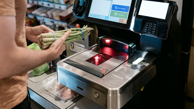 Person scanning asparagus groceries at a self-checkout station