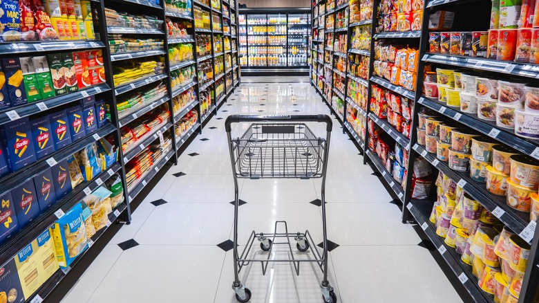 An empty shopping cart in the middle of a grocery store aisle