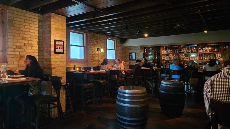 Restaurant interior with low lighting and patrons at high-top tables