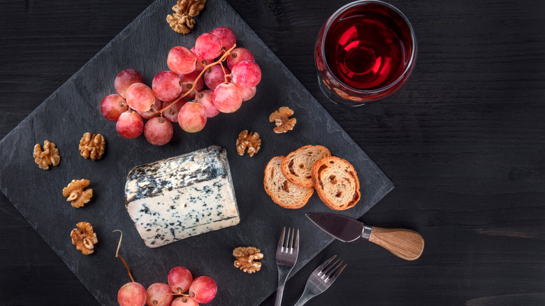 Cabrales blue cheese, grapes, red wine, baguette slices on a dark background