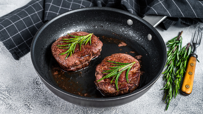 Filet mignon in a pan with herbs
