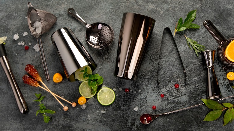 Various bartending equipment and garnishes on grey background