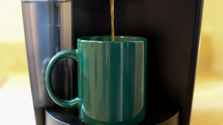 Keurig brewing coffee into a green coffee mug
