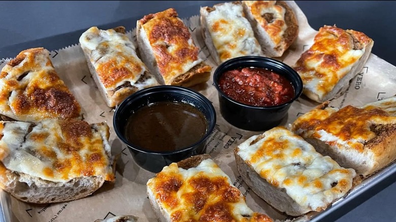 Cheese-covered gravy bread on paper and metal tray