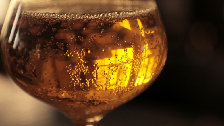 Carbonation rising from golden liquid in glass