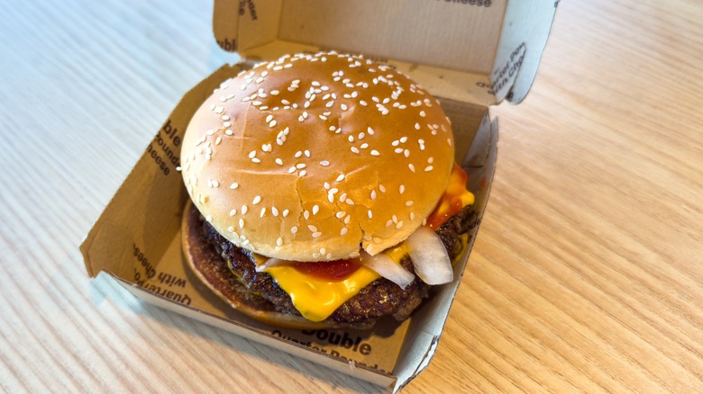 A McDonald's Quarter Pounder With Cheese nestled in an open cardboard box.