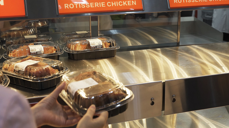 Holding rotisserie chicken against half-empty shelf