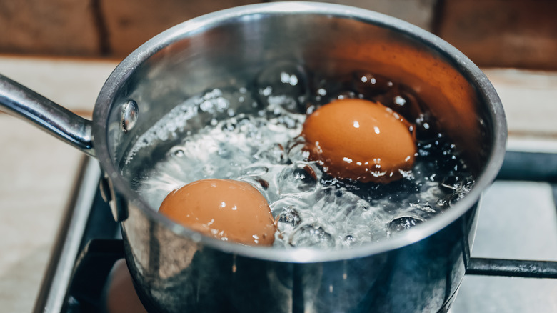 two eggs simmering in a pot of water