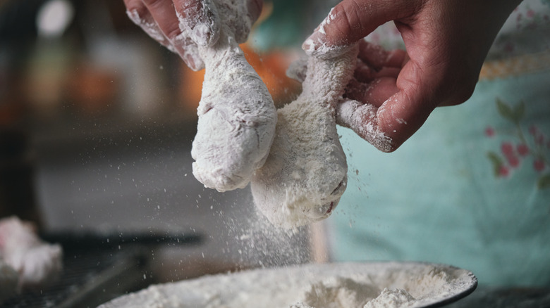 Chicken being dredged in flour