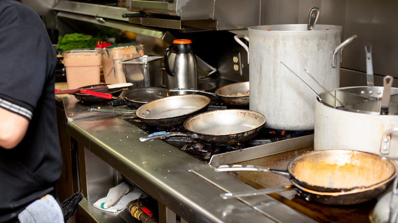 Messy restaurant kitchen with dirty pans