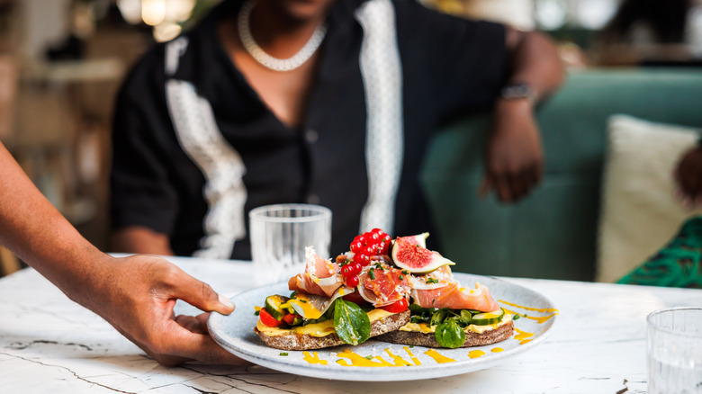 A plate of colorful bruschetta placed in front of a diner at a restaurant