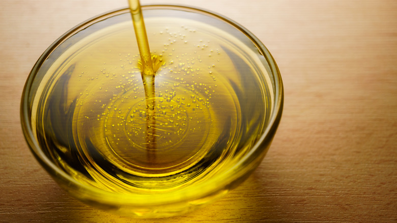 Clear bowl full of thick oil on wooden table