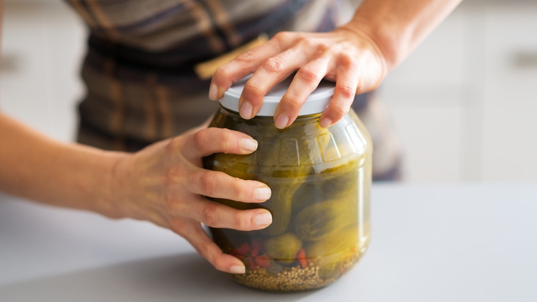 person trying to open jar of pickles