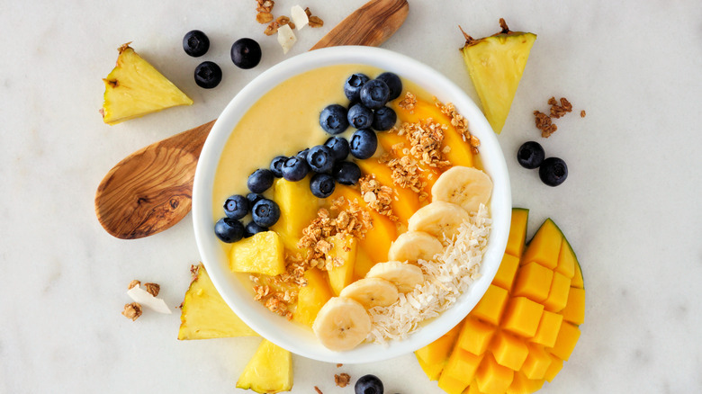 top-down view of a smoothie bowl with blueberries, pineapple, mango, bananas, and shaved coconut