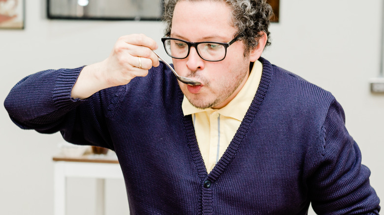 Person taste testing food with spoon