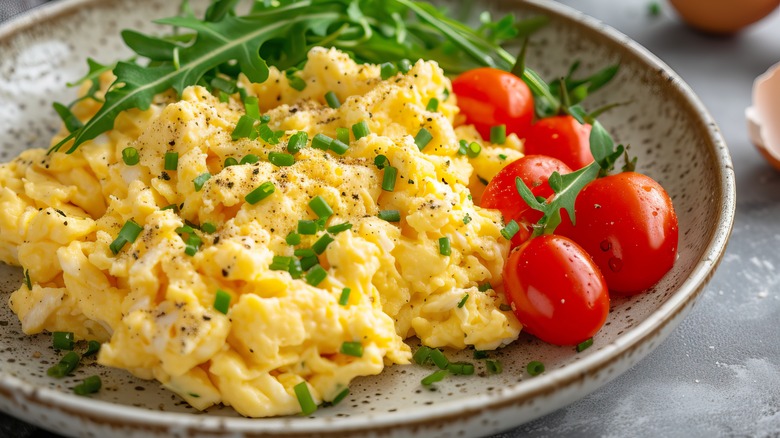 Scrambled eggs on plate with tomatoes and greens