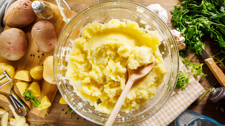 Bowl of mashed potatoes with a wooden spoon