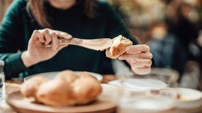 Woman applies butter on a piece of bread at a restaurant