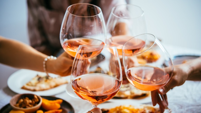 Friends toasting with rose over dinner.