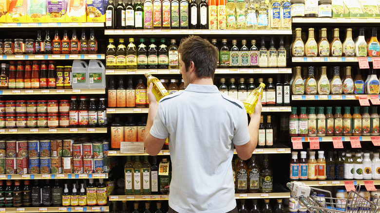 Customer in supermarket deciding between olive oils