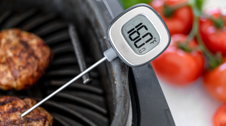 Meat thermometer sticking into burger