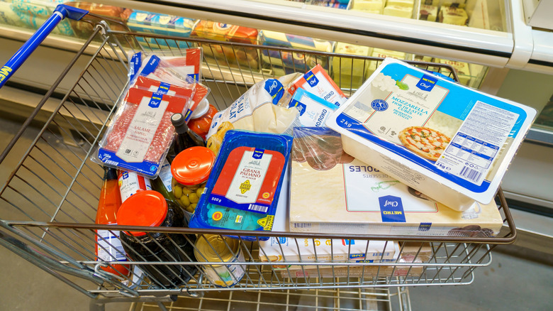 A shopping cart with perishable items like meat and cheese on top