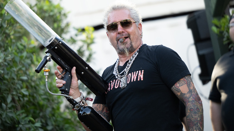 Guy Fieri in Flavortown tshirt holding an air gun