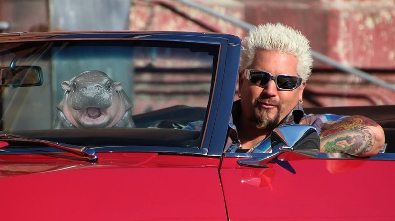 Guy Fieri behind the wheel of a red sports car