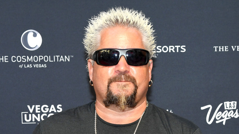 Guy Fieri wearing sunglasses and a black t-shirt