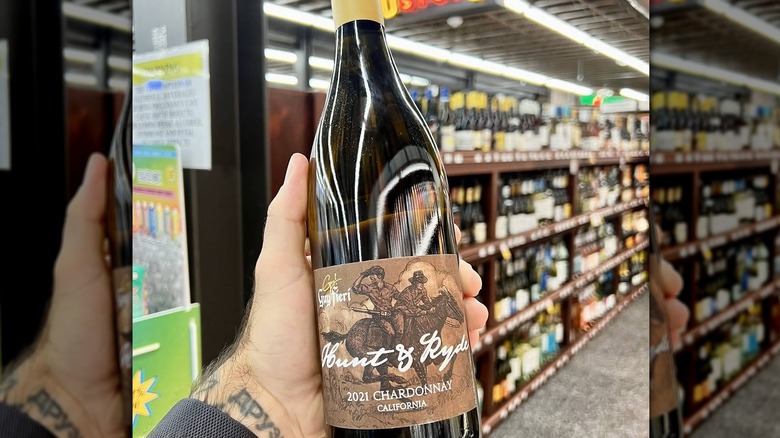 Close-up of a hand holding a bottle of Hunt & Ryde wine