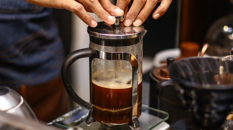 Person using French press coffee maker