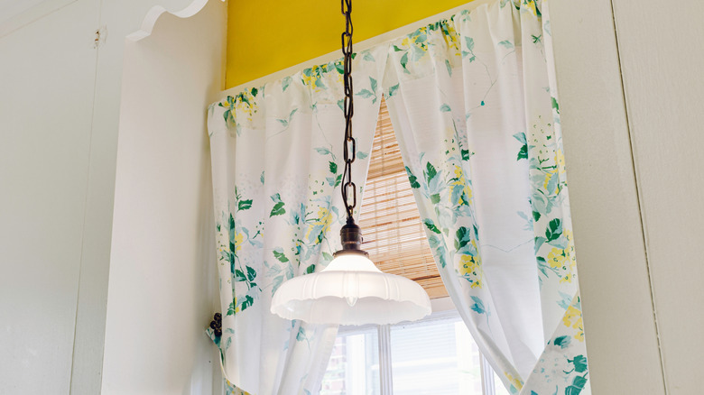 Floral curtains with a vintage, white, scalloped light fixture.