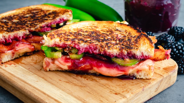 Grilled cheese with blackberries and peppers on wood cutting board