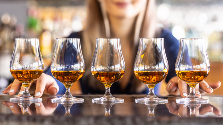 Bartender serving five snifters of whiskey