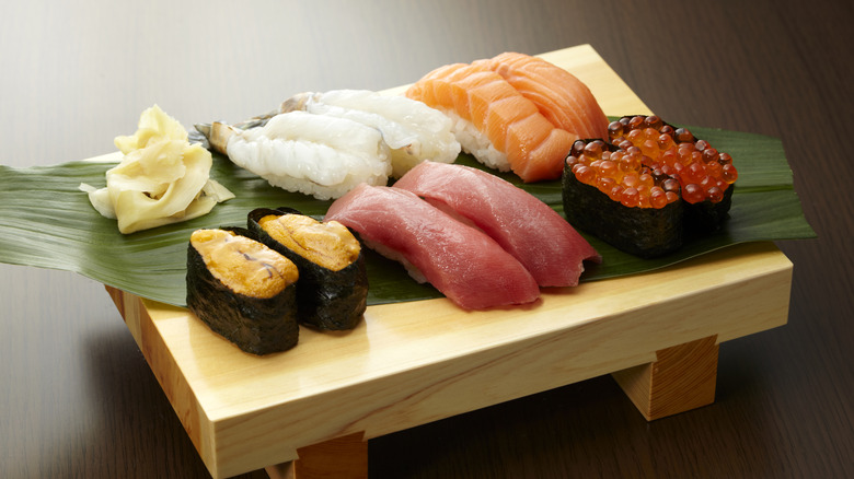 Various sushi and sashimi on wooden board