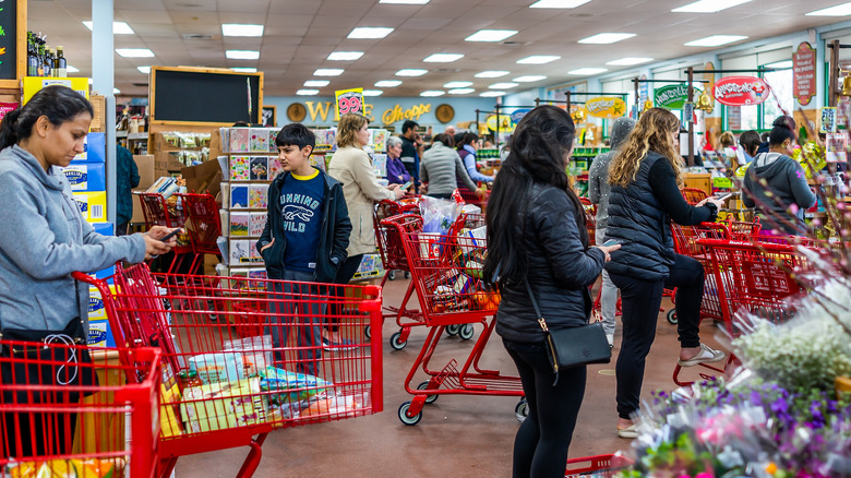 Lines of people with red grocery carts waiting at registers.
